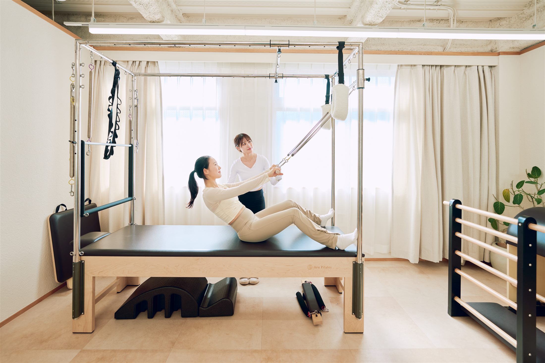 自然光の入るスタジオでマシンピラティスを受ける様子